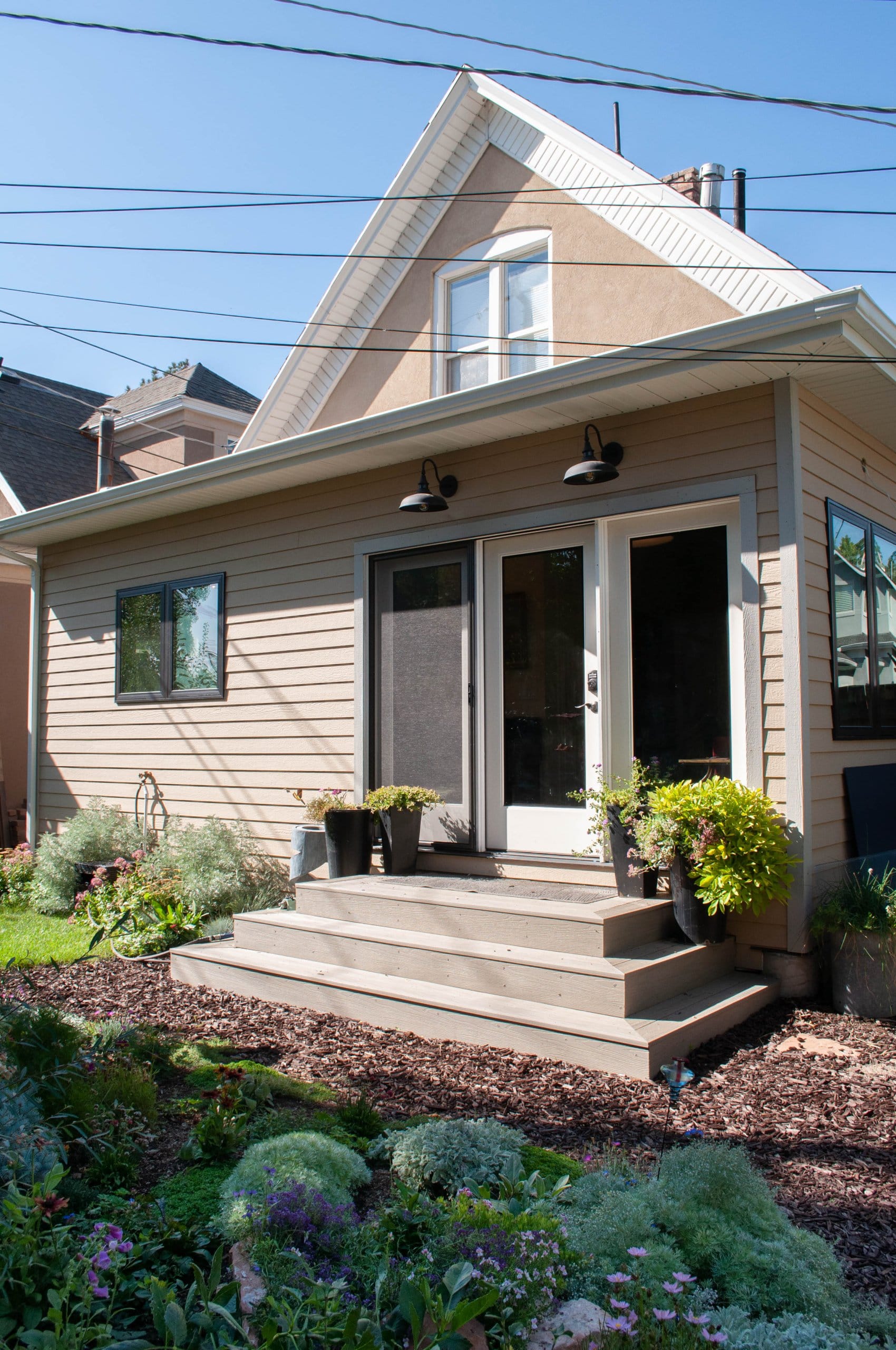 Exterior of the addition with new landscaping. The addition includes a new back door with three steps leading to the yard.