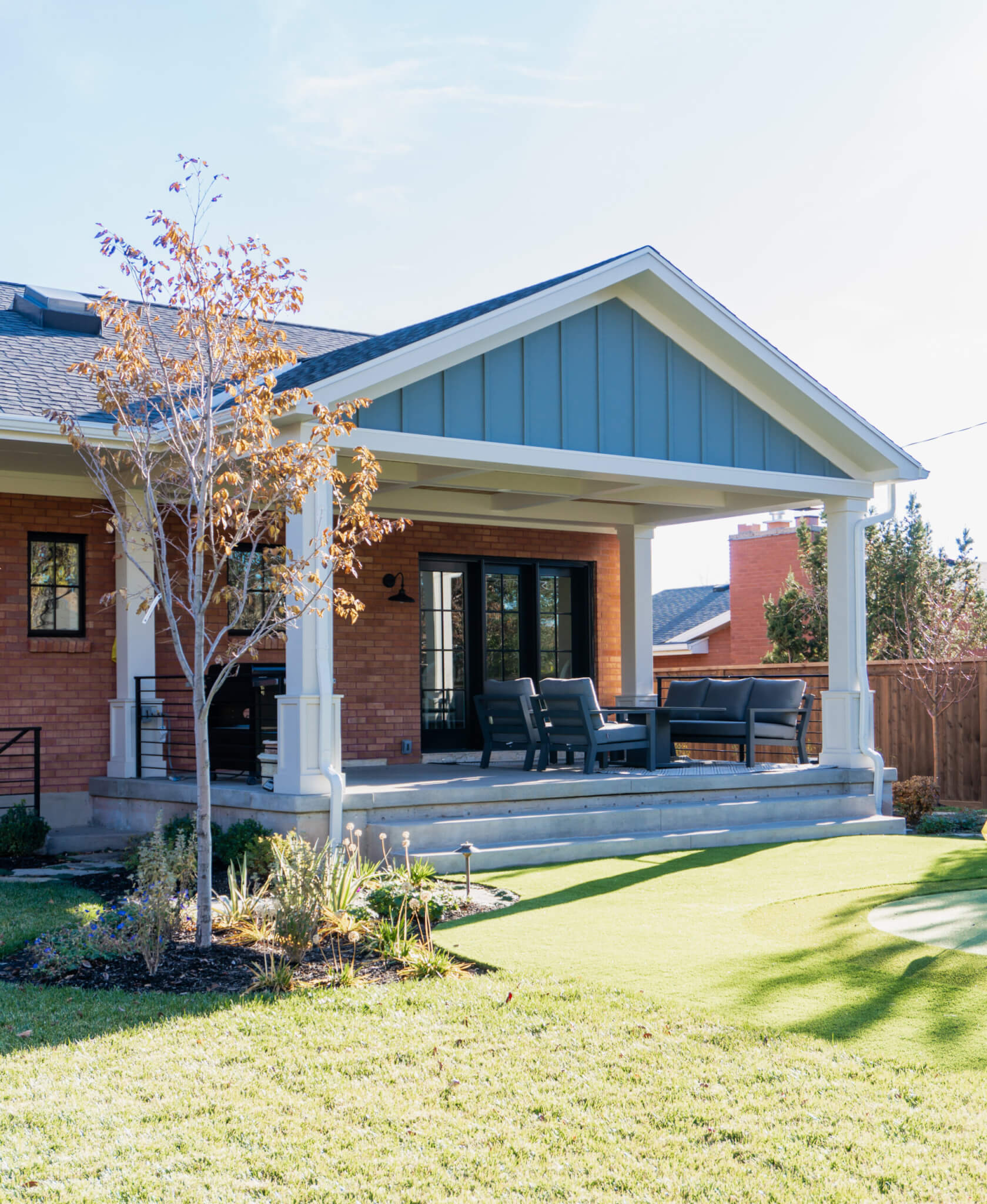 Backyard covered patio with grill and seating.