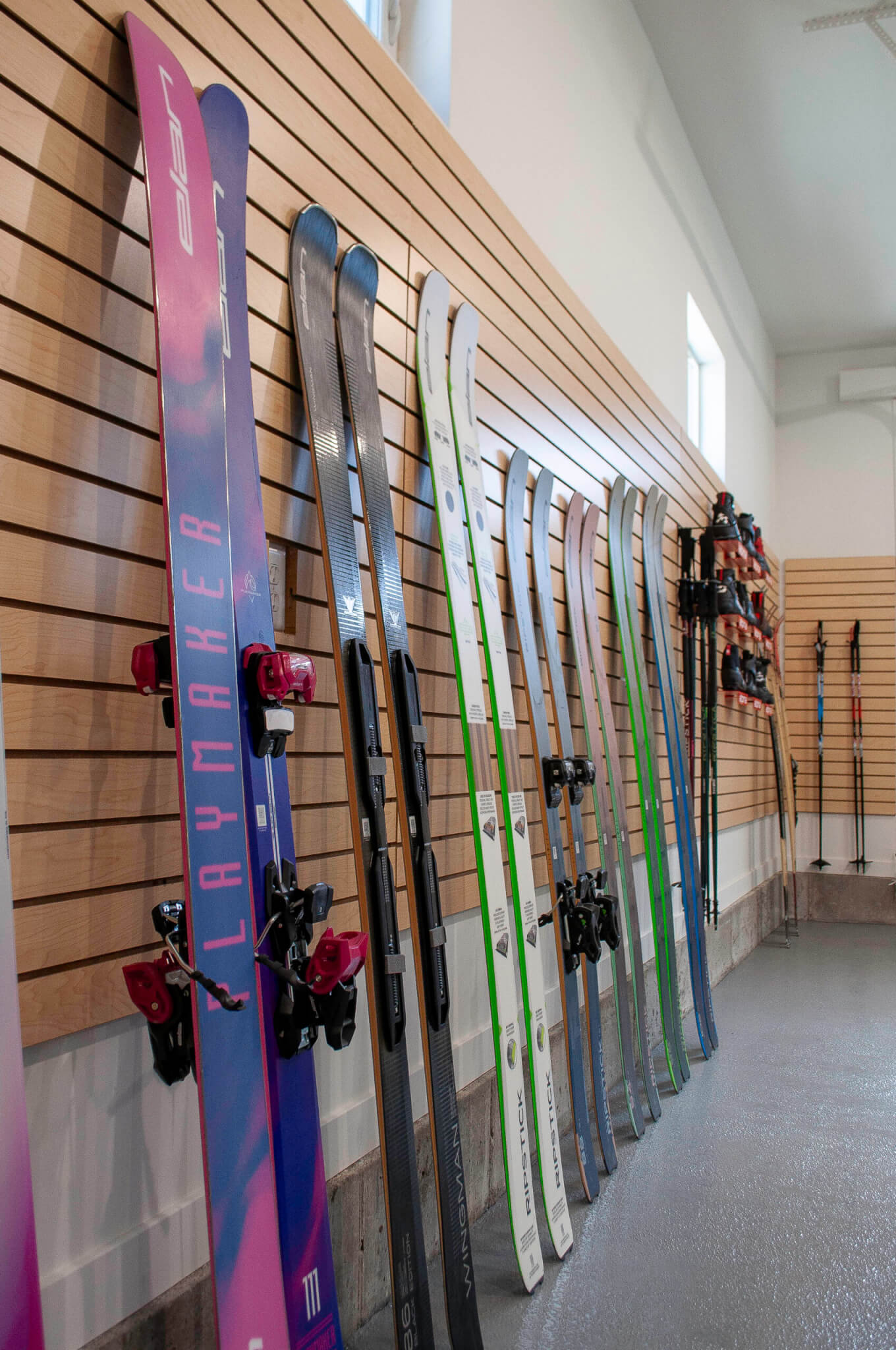 Pairs of skis lined up on the wall inside the garage.