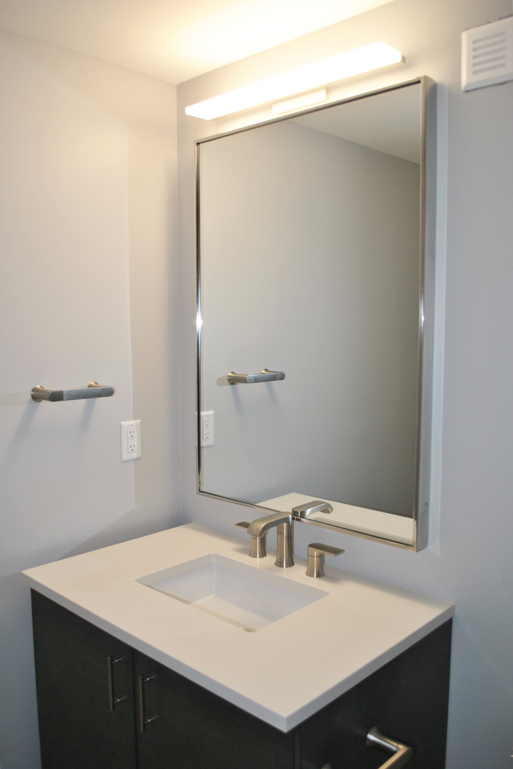 Bathroom vanity sink with a mirror and light above.