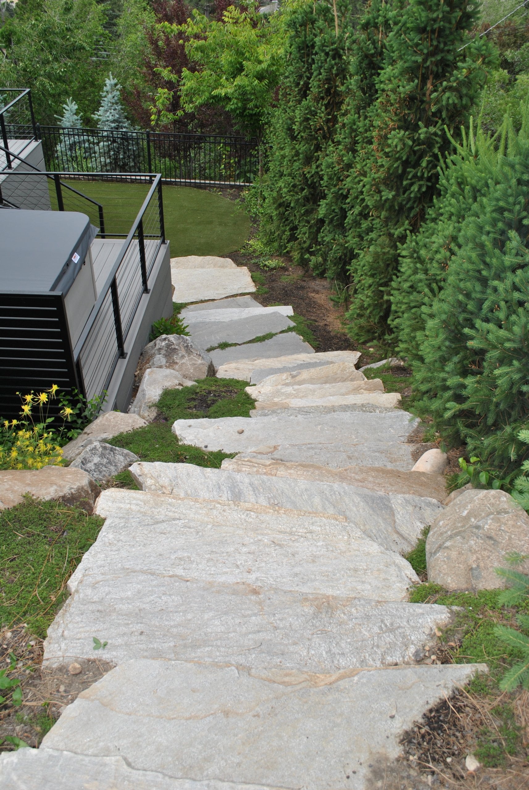 Stone staircase down the side yard. To the left, part way down the steps, is a deck with a hot tub.