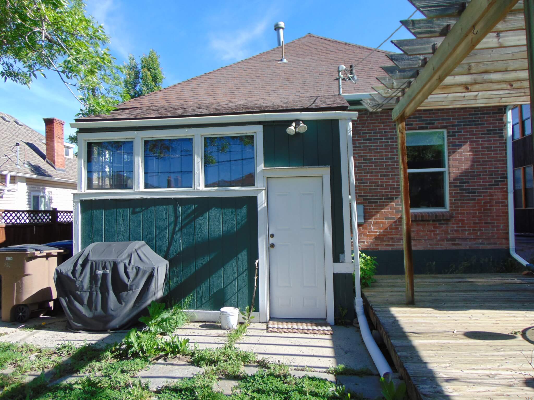 Exterior of the existing addition with a wood deck and pergola on the right.