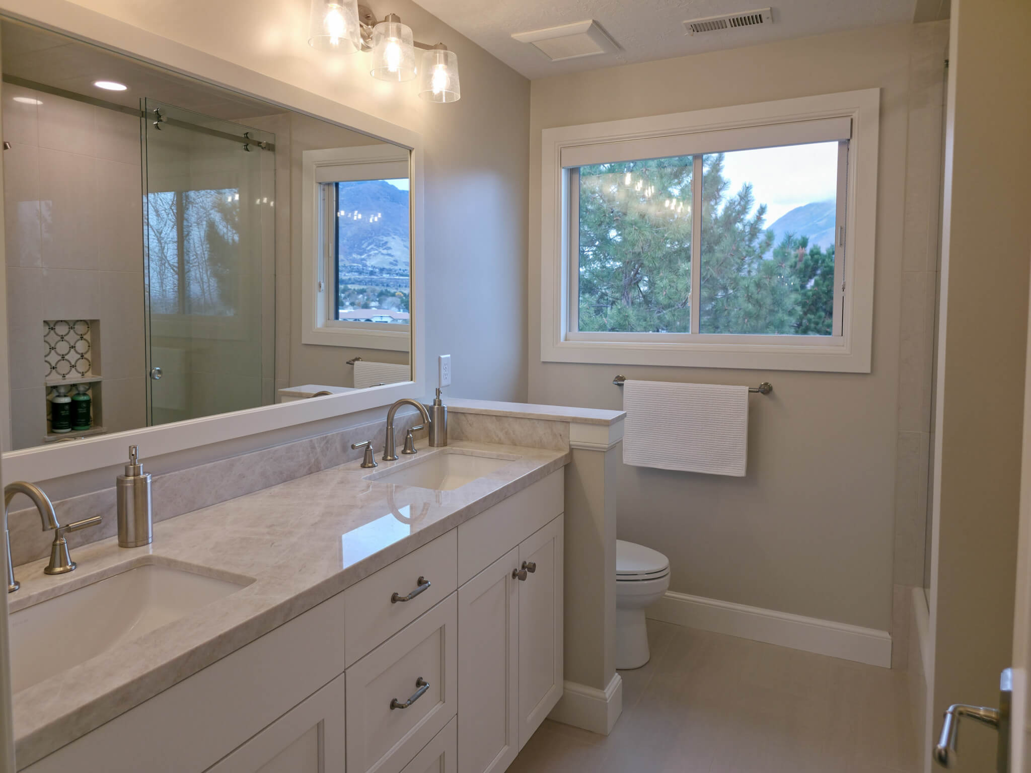 Bathroom with a double vanity and window looking toward the mountains.
