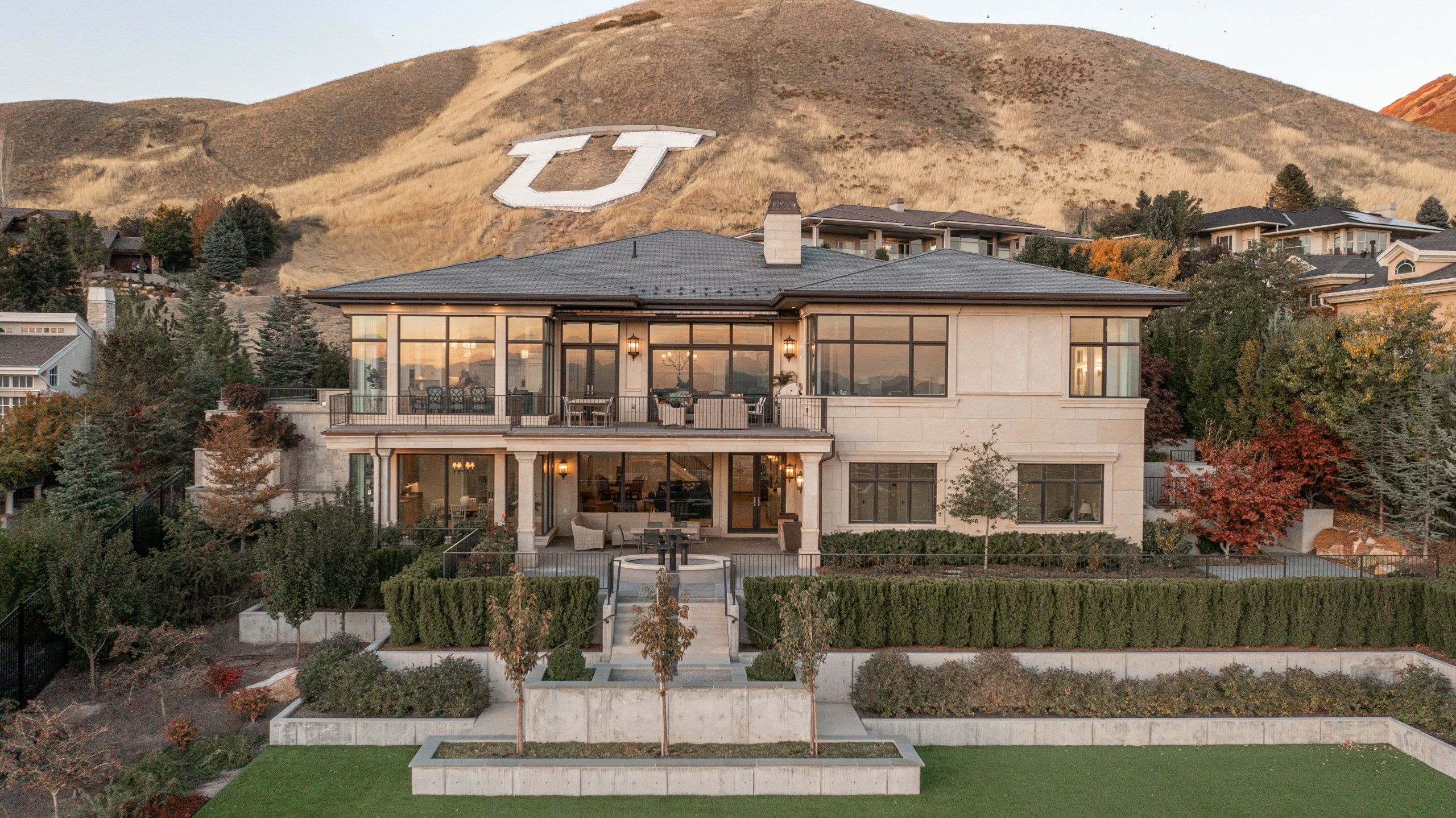 Back exterior of renovated home with updated landscaping. The home sits on the side of a mountain and includes a covered patio under the deck.