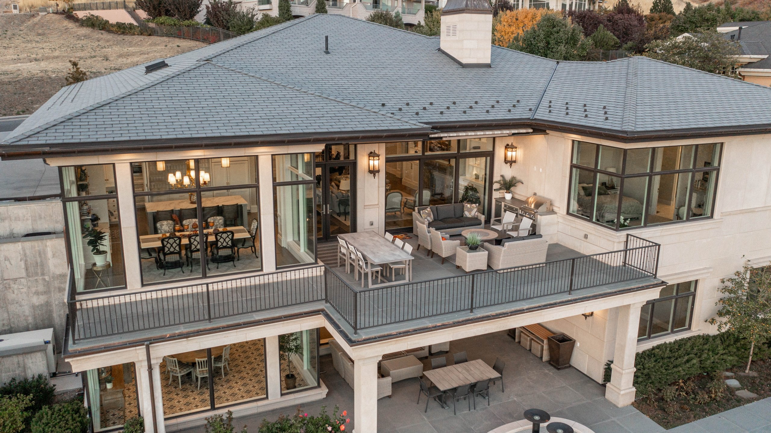Exterior of a house with a covered patio under the deck. Both spaces include outdoor furniture and windows with views to the interior of the home.