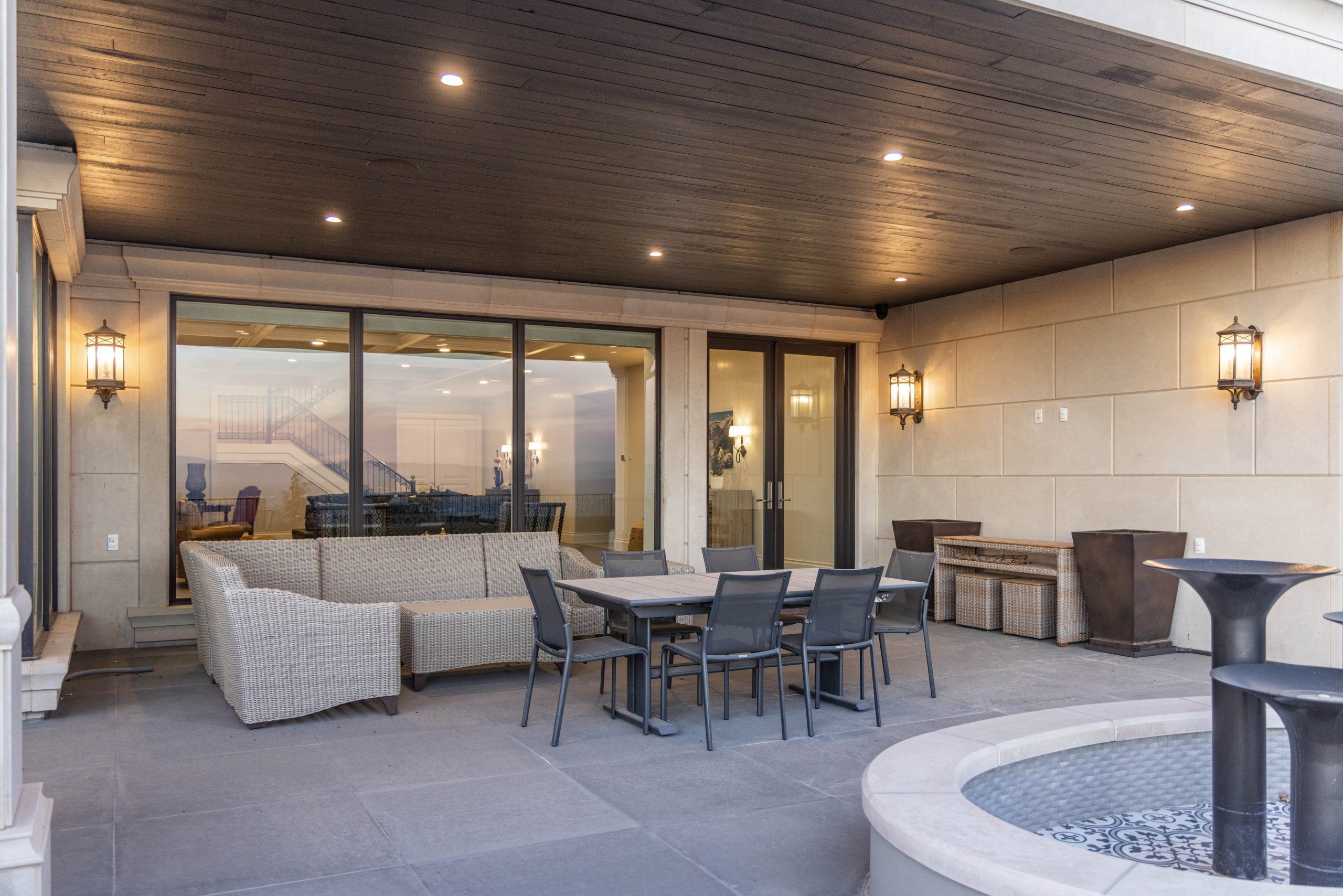 Covered patio with outdoor furniture, a fountain, and windows and doors to the interior of the home.