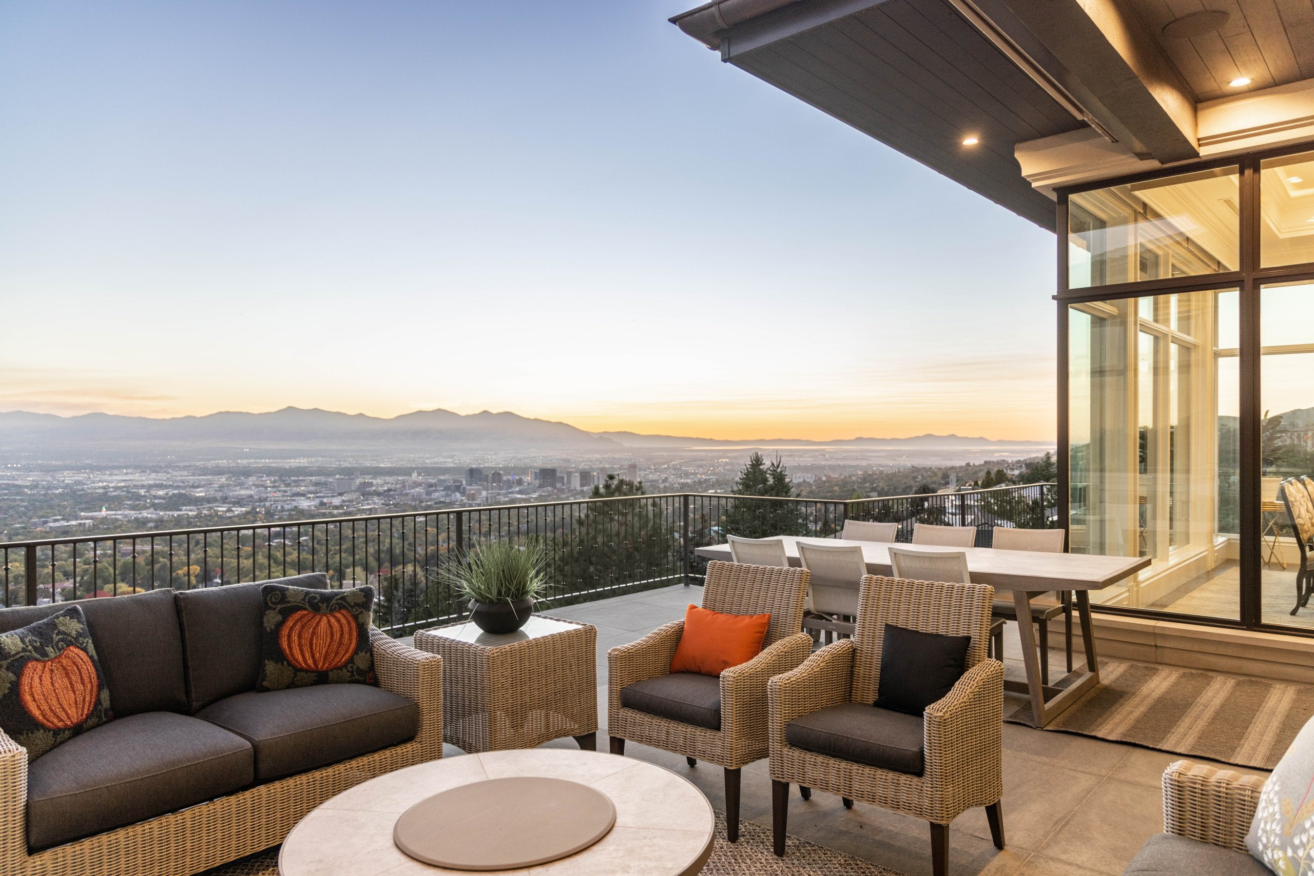 Large deck with outdoor furniture and a railing. The deck overlooks the valley at sunset.