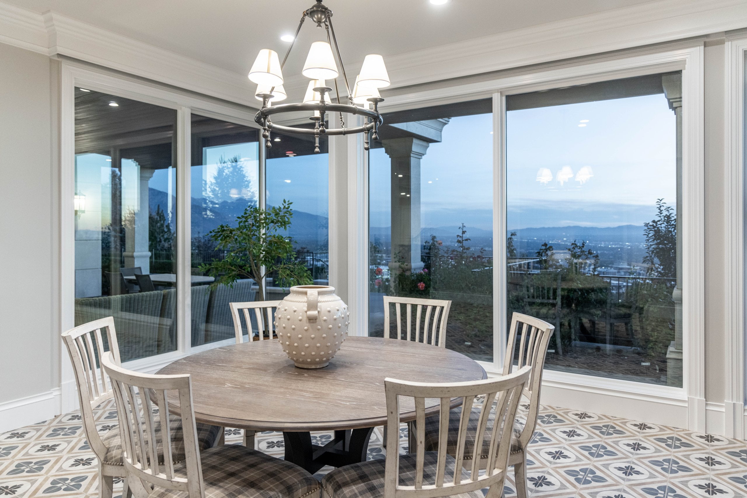Round table with six chairs on the tile flooring and windows behind that overlook the valley.
