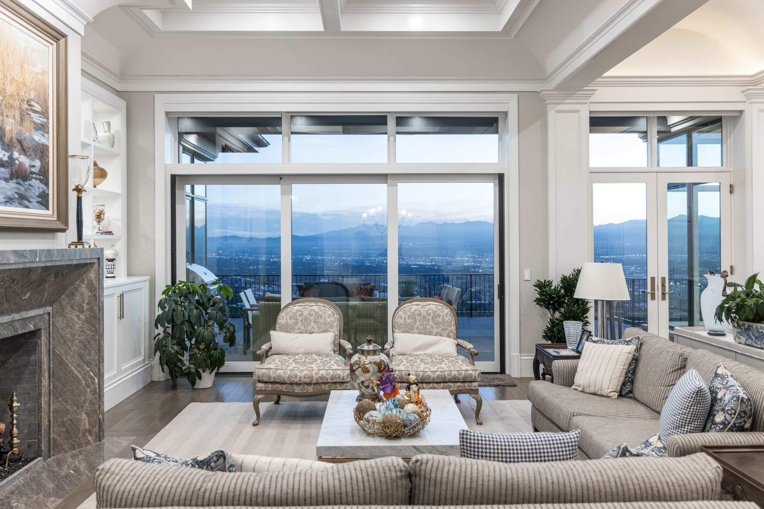 Living room with large windows and doors out to the deck and furniture in front of the fireplace.
