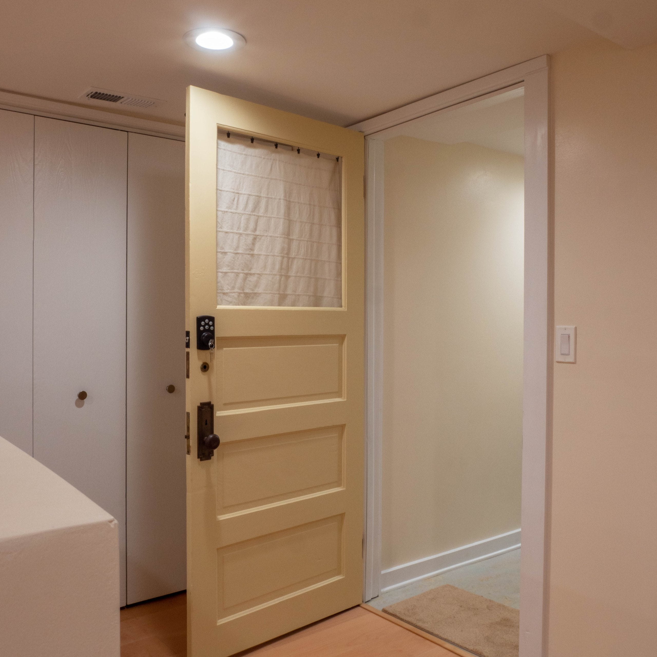 Basement apartment entry door with a key pad and closet doors behind.