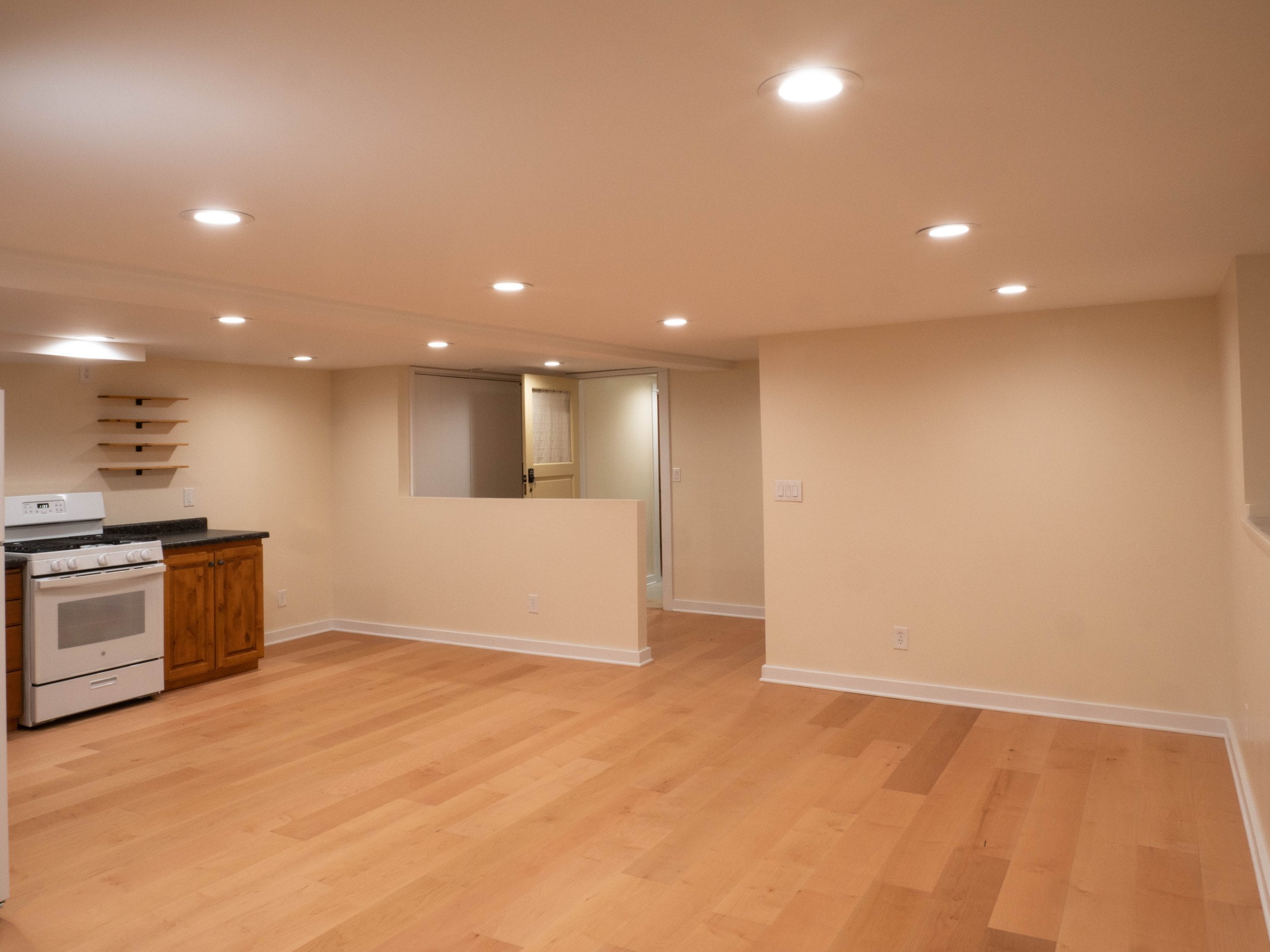 Unfurnished basement apartment after the renovation with a family room, entry, dining space, and kitchen.