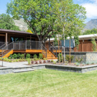 Thumbnail of http://Backyard%20of%20a%20mid-century%20home.%20The%20yard%20features%20grass,%20a%20patio%20with%20a%20firepit,%20a%20hot%20tub,%20and%20a%20deck%20built%20around%20a%20tree.