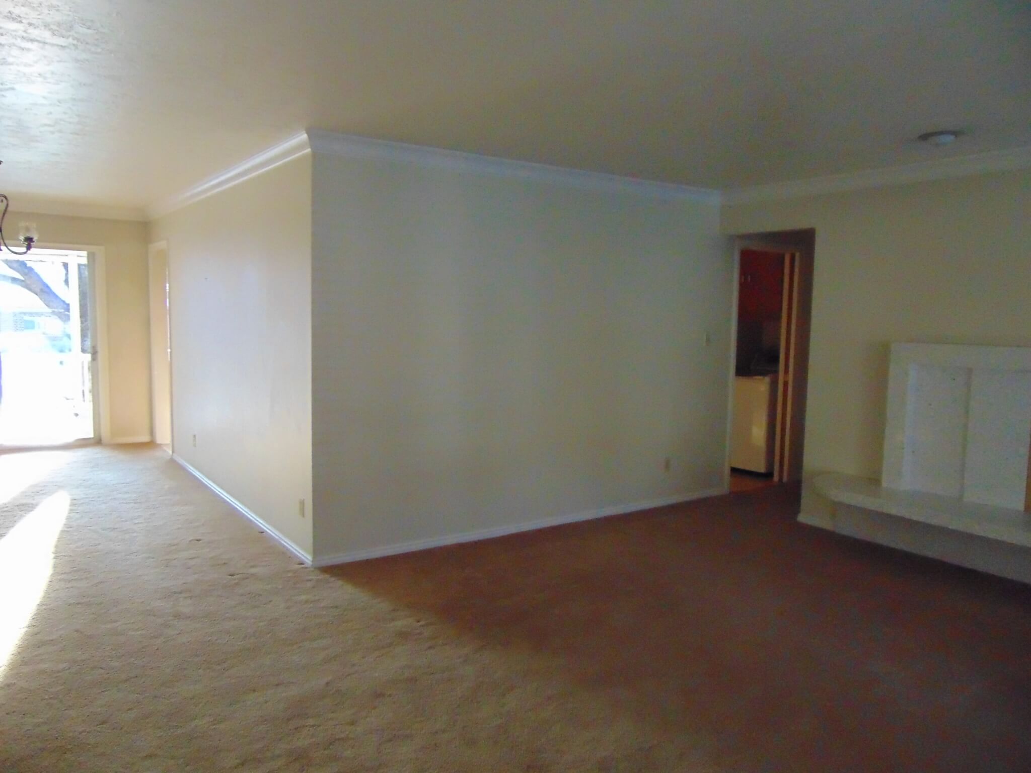 Living Room before the remodel with a wall separating the space from the kitchen and carpet.