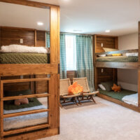 Thumbnail of http://Basement%20bunk%20room%20with%20two%20sets%20of%20built-in%20bunks%20for%20a%20total%20of%20four%20beds%20and%20two%20chairs%20in%20front%20of%20the%20window.