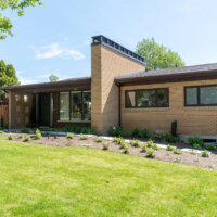 Thumbnail of http://Mid-century%20exterior%20of%20a%20brick%20home%20with%20a%20large%20chimney,%20front%20porch,%20and%20updated%20landscaping.