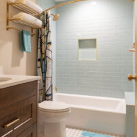 Thumbnail of http://Guest%20bathroom%20with%20a%20tub%20and%20shower%20combination,%20toilet,%20and%20vanity.%20The%20design%20features%20a%20light%20blue%20tile%20and%20gold%20fixtures.