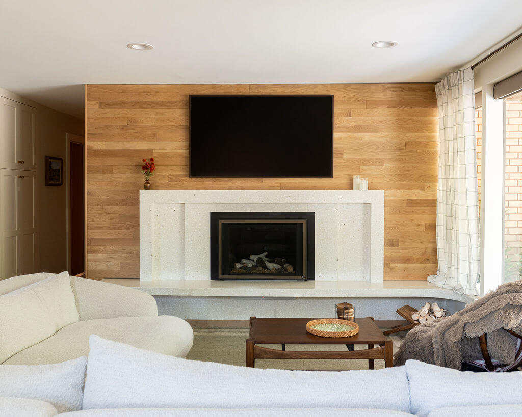 Mid-century modern fireplace with wood paneling on the wall.
