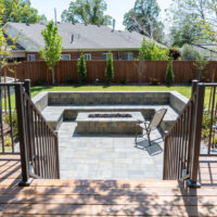 Thumbnail of http://Stairs%20leading%20down%20from%20the%20deck%20to%20the%20yard%20and%20patio%20with%20a%20built-in%20bench%20and%20fire%20pit.