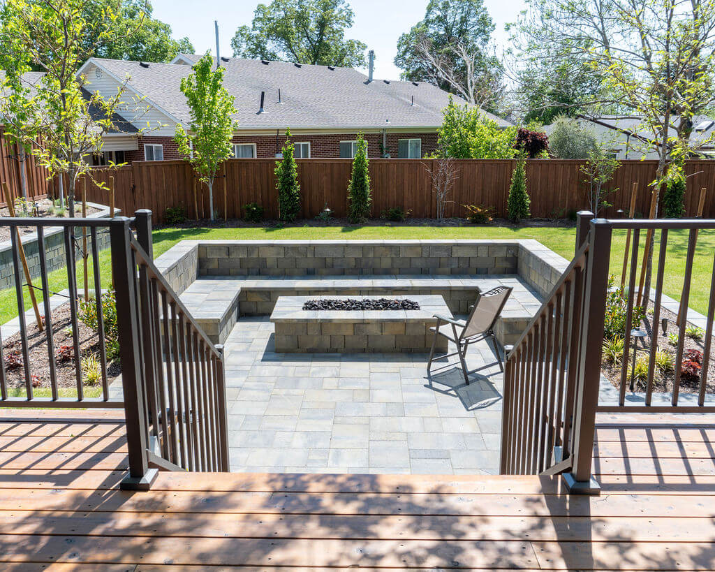 Stairs leading down from the deck to the yard and patio with a built-in bench and fire pit.