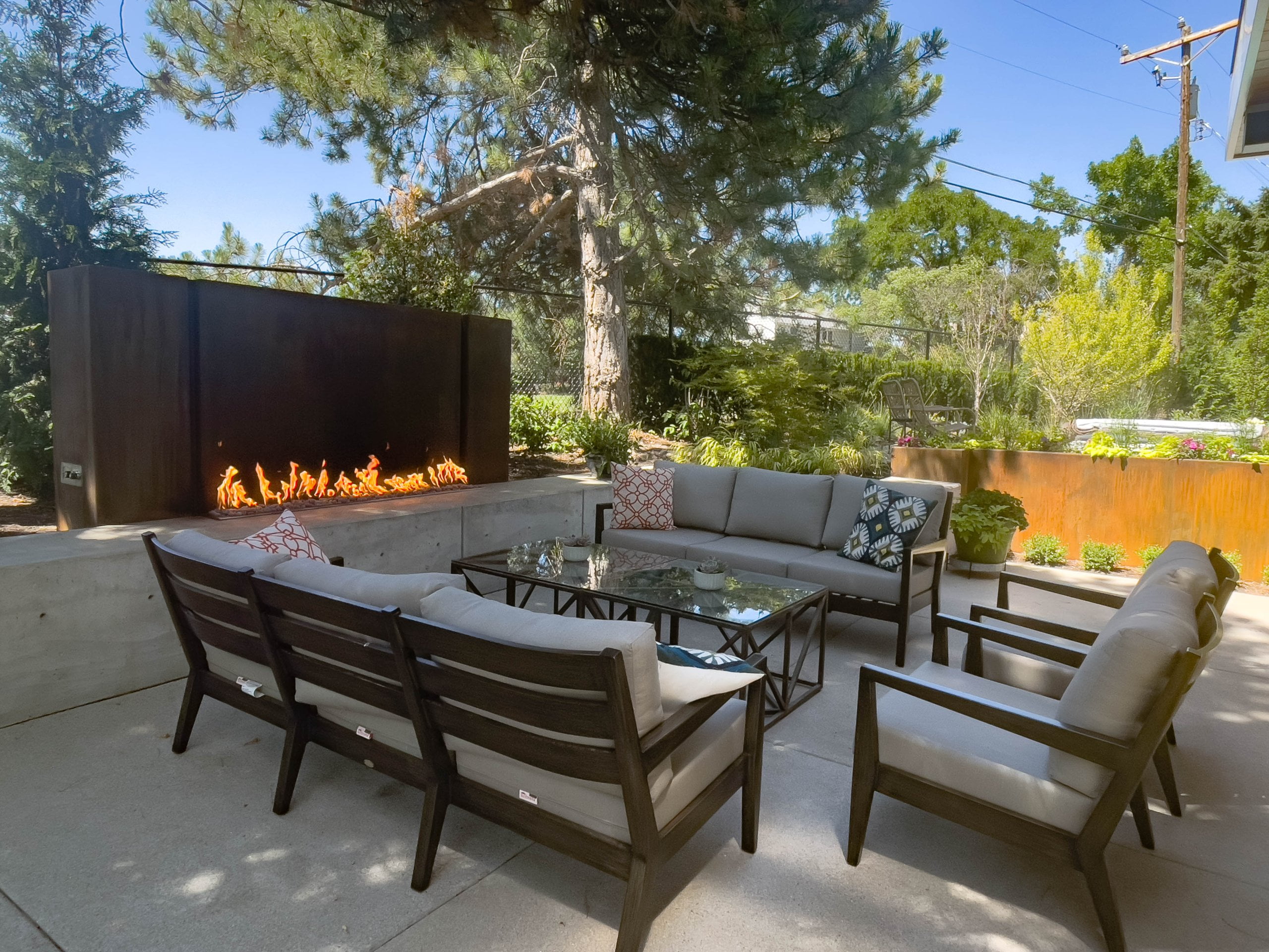 Outdoor fireplace with two couches, chairs, and a coffee table in front.