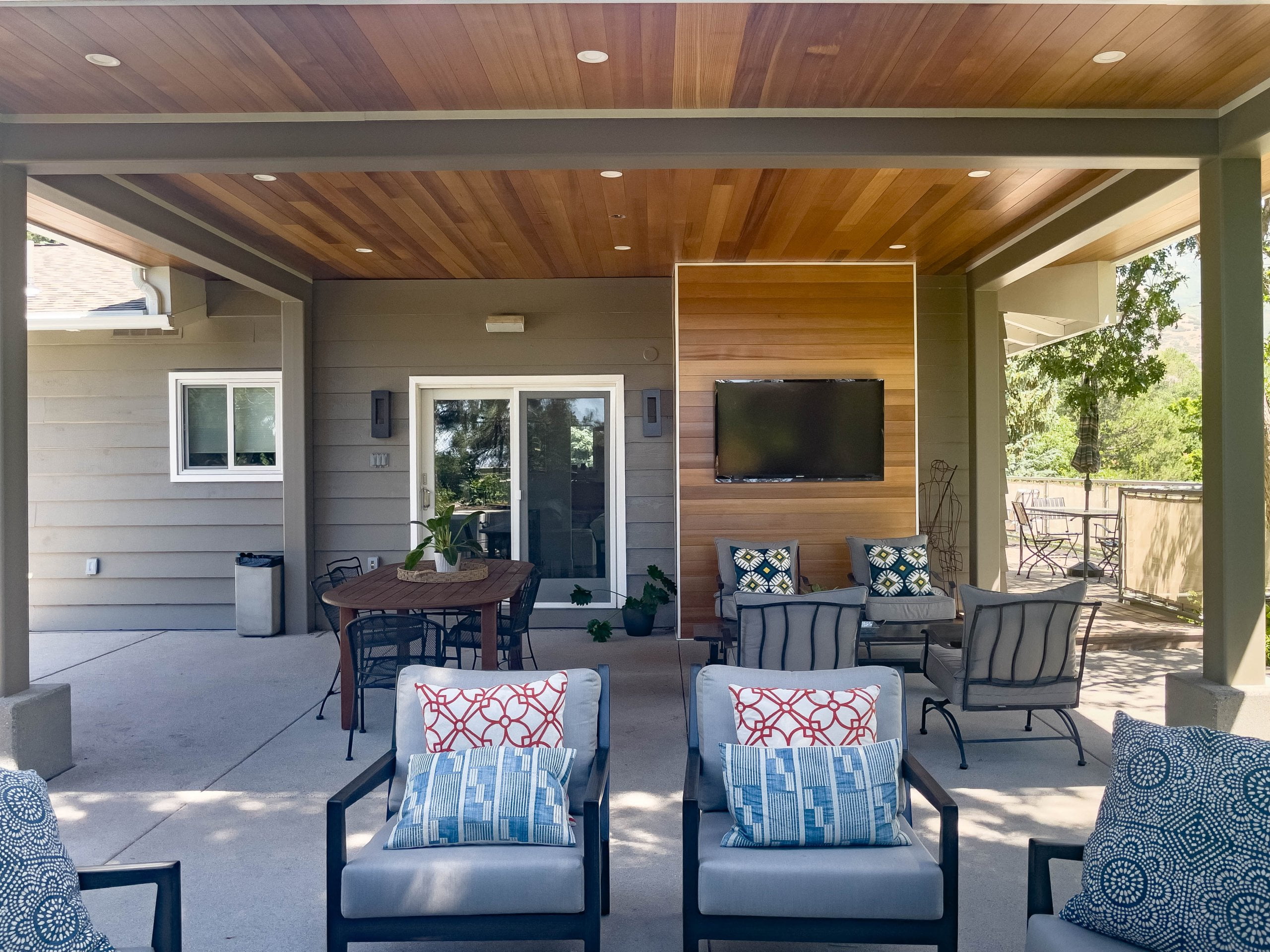 Covered patio with a TV, seating, and an outdoor table with chairs around it.