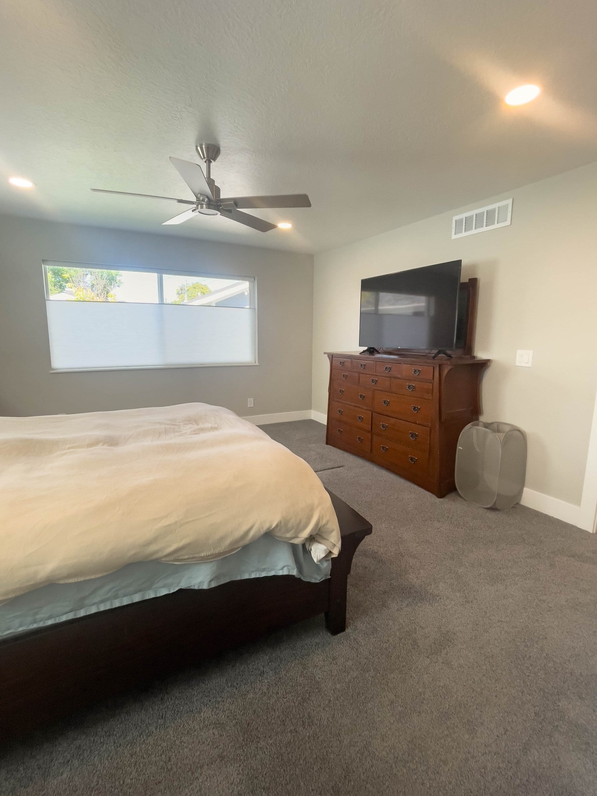 Bedroom with a ceiling fan, carpet, and large window.