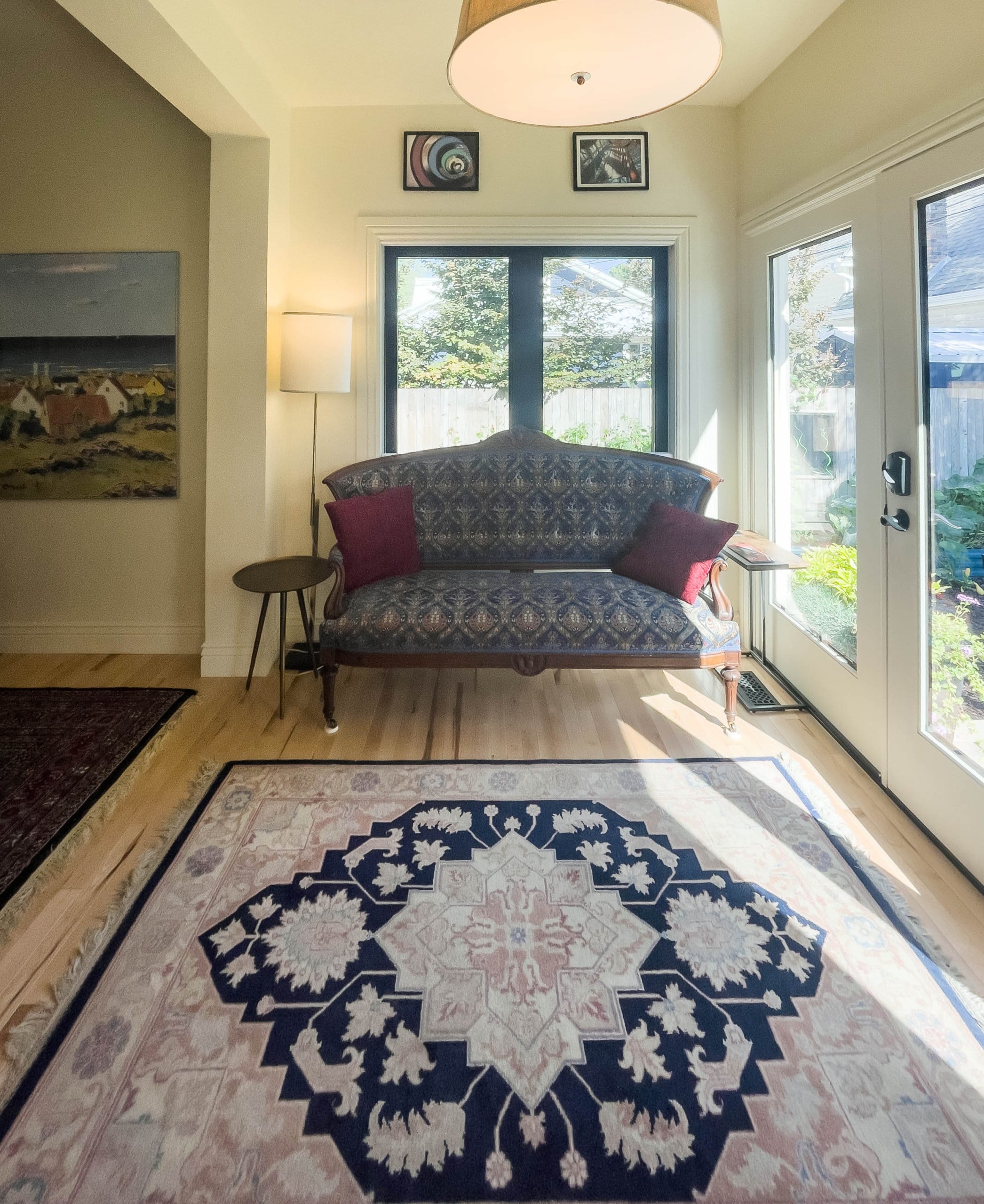 Couch in front of a window with a rug centered in front and a door to the right.