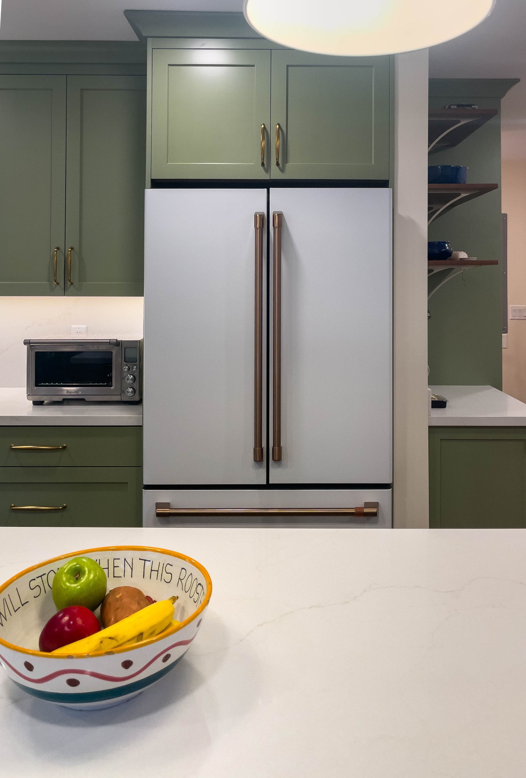 White fridge with green cabinet above.