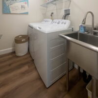 Thumbnail of http://Laundry%20room%20with%20side-by-side%20washer%20and%20dryer,%20a%20shelf%20above,%20and%20a%20sink%20to%20the%20side.