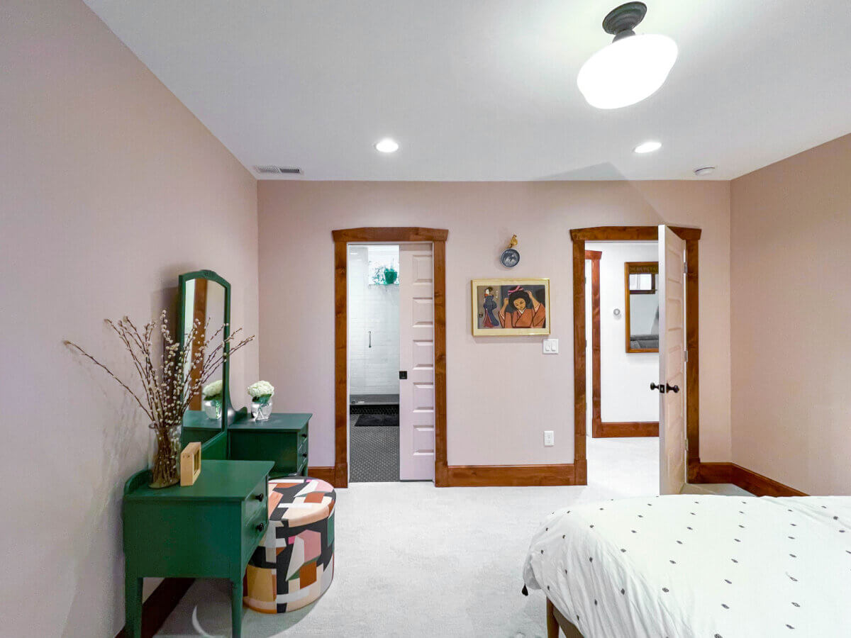 Basement bedroom renovation with a bed and desk looking to the hallway and bathroom