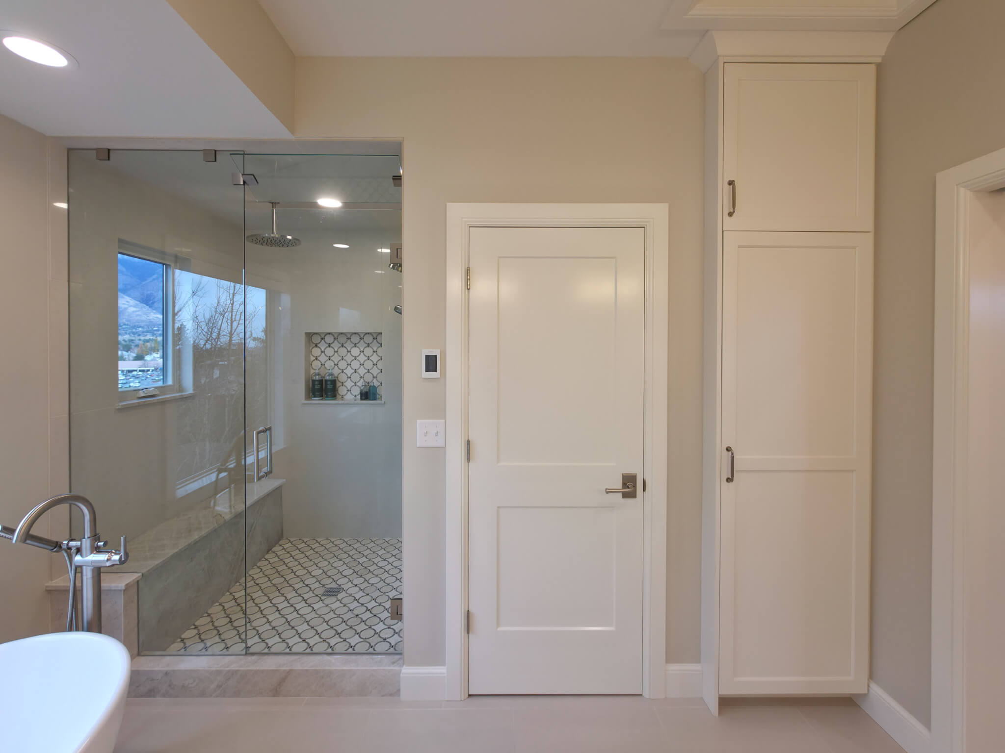 Primary bathroom looking toward the shower, toilet closet door, and built-in storage cabinet.