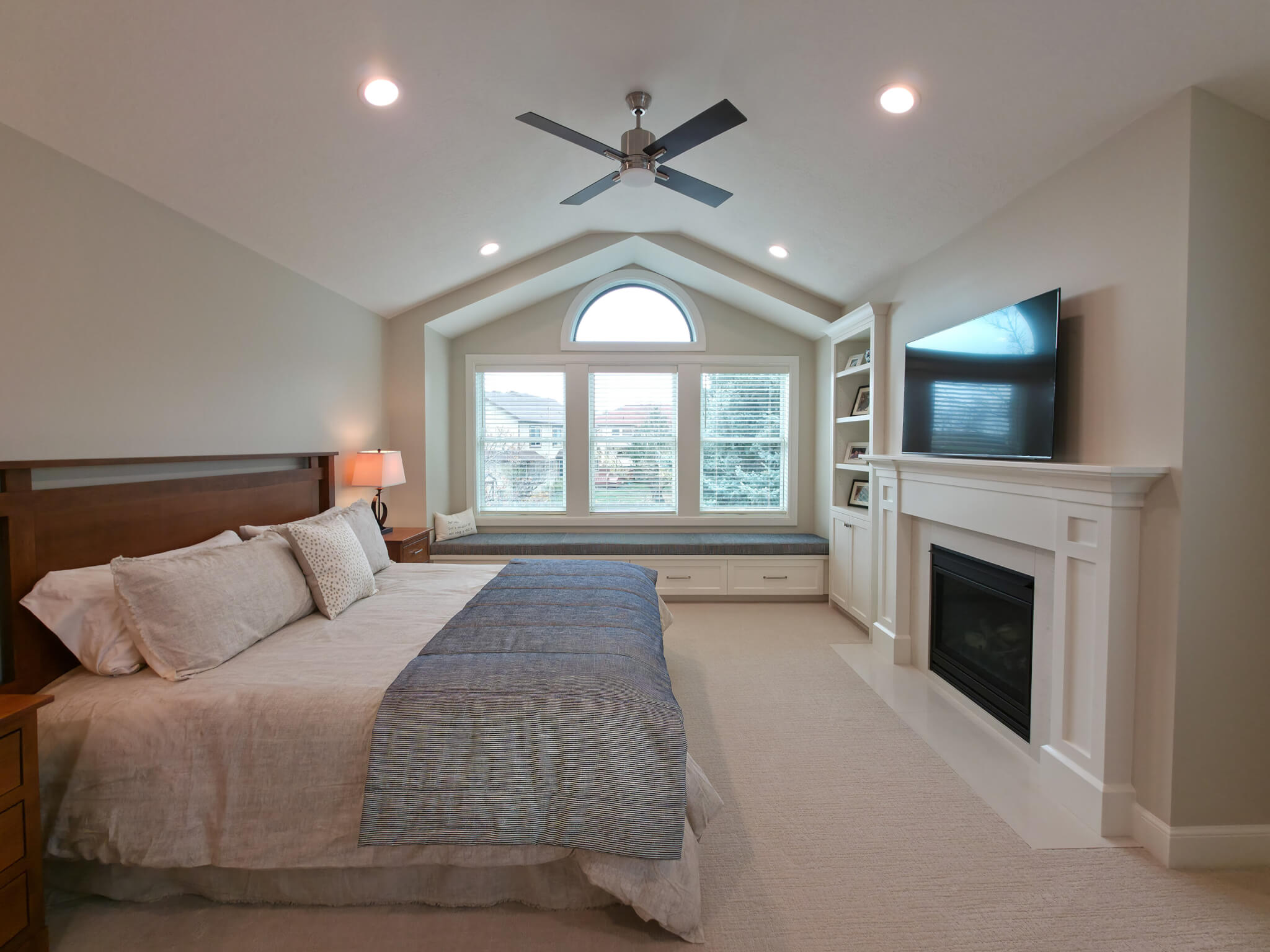 Large primary bedroom with vaulted ceilings, a fireplace, and built-in window seat.