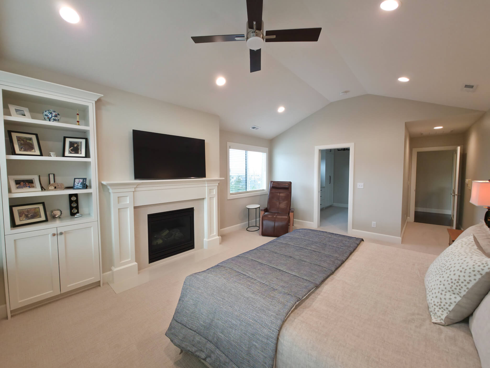 Primary bedroom with vaulted ceilings and a fireplace looking toward the door to the hallway and the door to the closet.