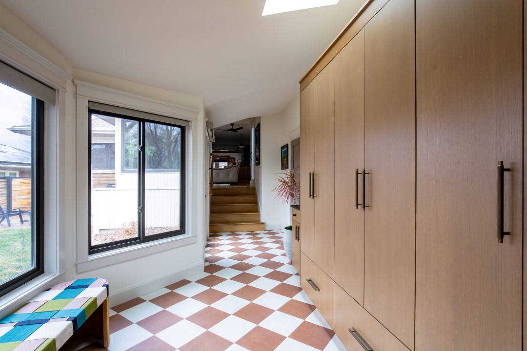 Mudroom after the remodel featuring a fun tile pattern on the floor, built-in cabinets, and lots of natural light.