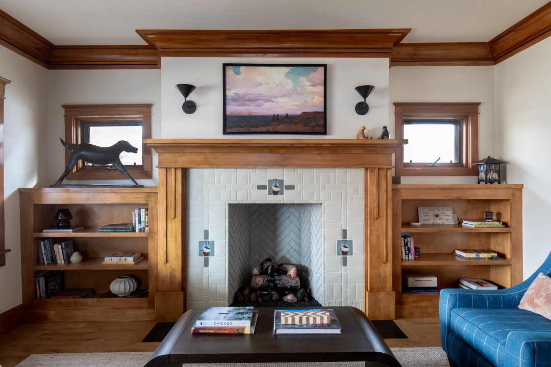 Historic home living room with wood details in the trim, casing, and built-in bookshelves on either side of the fireplace. The fireplace serves as a focal point with a beautiful tile surround. 