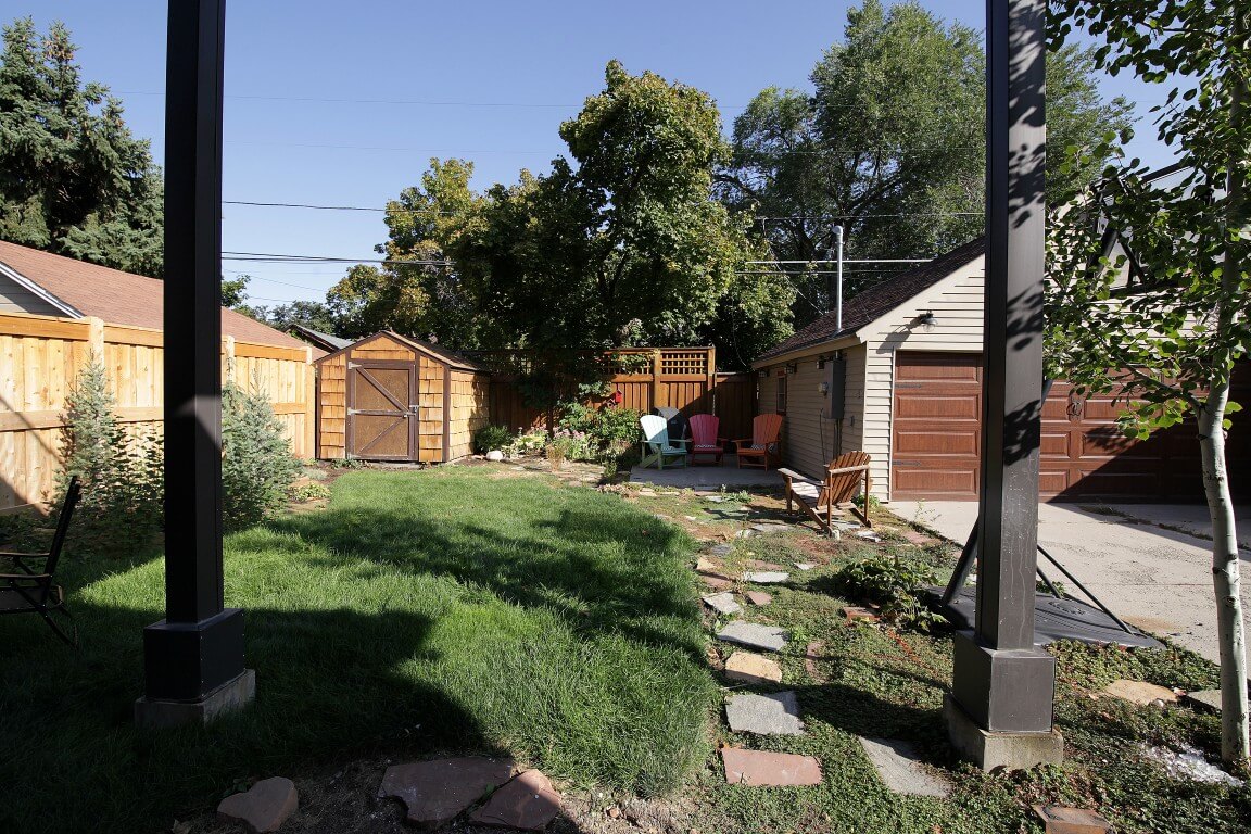 Backyard before a pool was added. Features a grass area with some stones, a shed, and a garage.