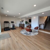 Thumbnail of http://Large%20basement%20great%20room%20with%20four%20chairs,%20the%20stairs,%20a%20small%20bar,%20and%20a%20workout%20area.