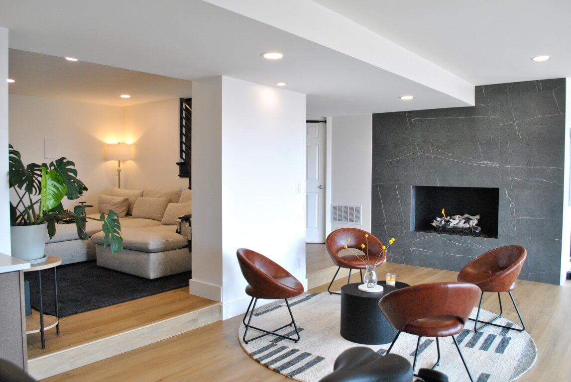 Sitting area in front of the fireplace. Four chairs are placed around a coffee table and on a round rug.