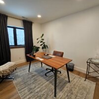 Thumbnail of http://Basement%20office%20with%20a%20desk%20and%20chair%20in%20the%20center.%20A%20window%20is%20framed%20by%20curtains%20to%20the%20side.