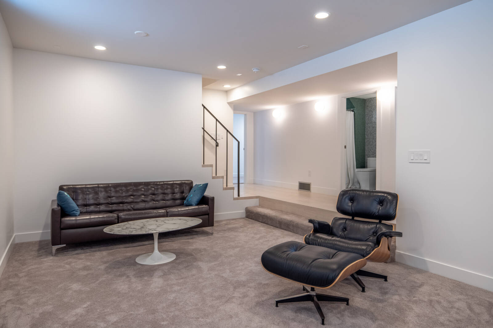 Sunken family room in the basement that is furnished with a couch, coffee table, and chair.