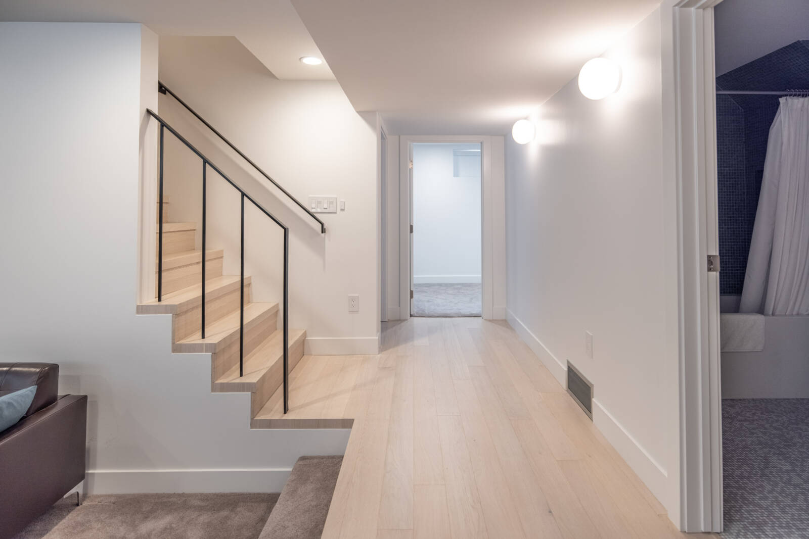 Hallway in the basement that leads to a bedroom, bathroom, stairs, and the sunken family room.