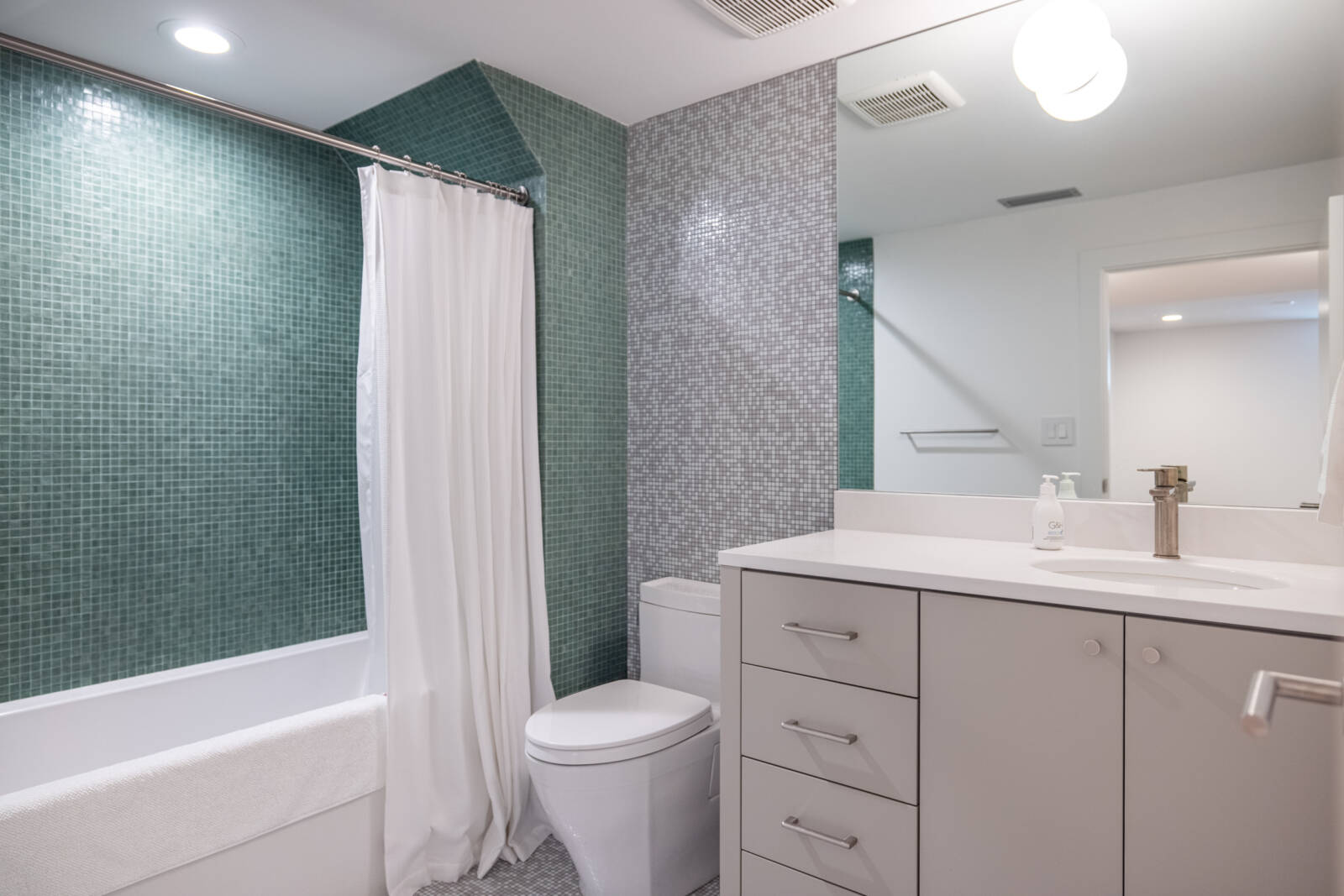 Modern bathroom with a large vanity, toilet, and shower and tub combination.