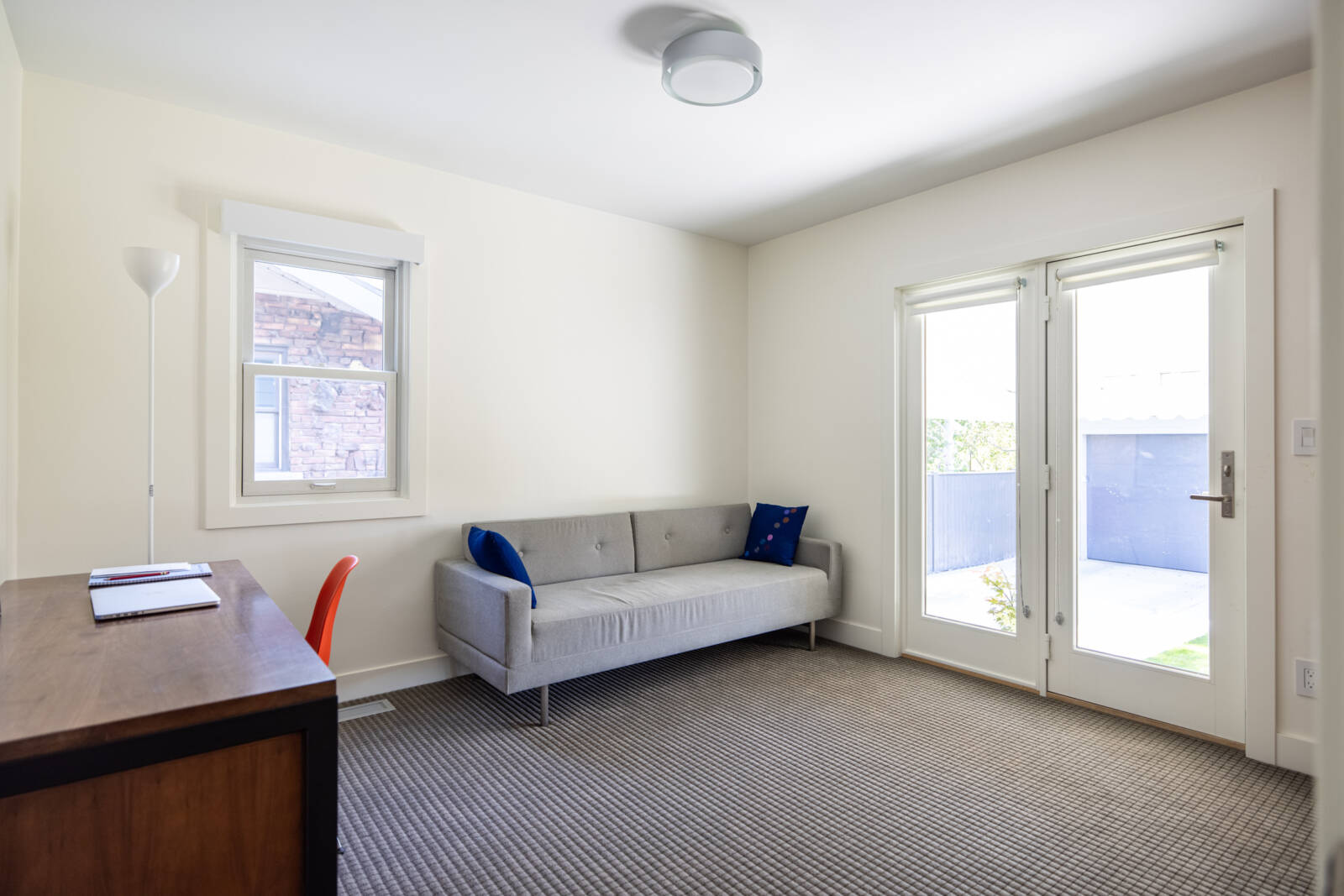 Home office with a door to the backyard, couch, and desk.