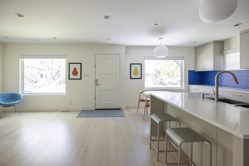 Open concept kitchen, dining room, and living room. The kitchen includes a large island and blue tile backsplash.