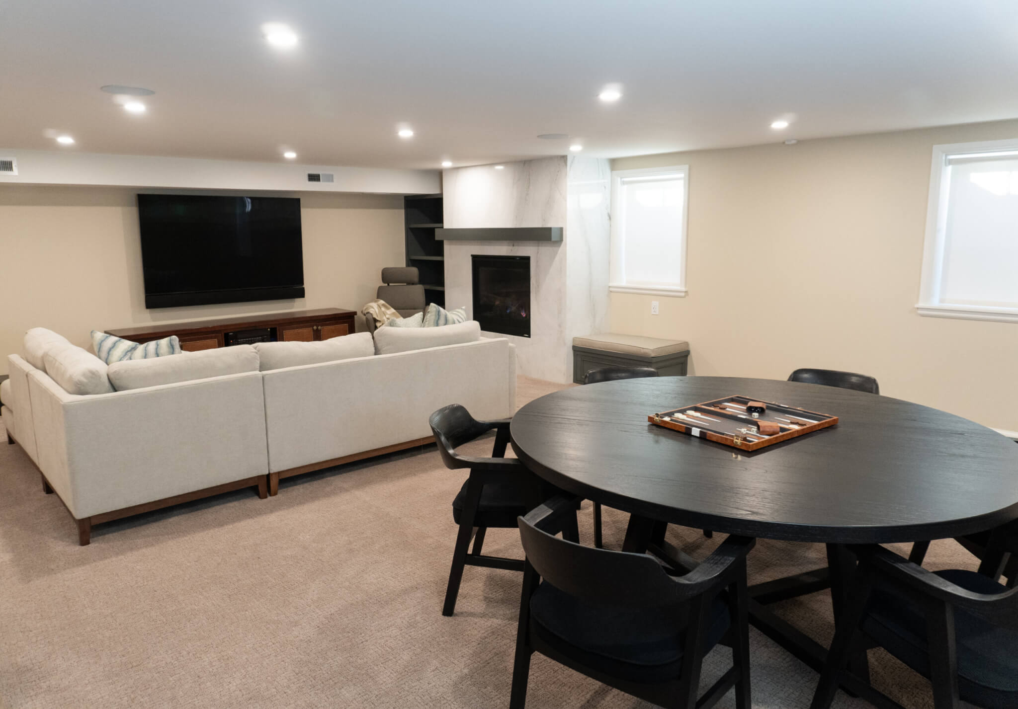 Basement family room with a large table for games and a couch by the tv and fireplace.