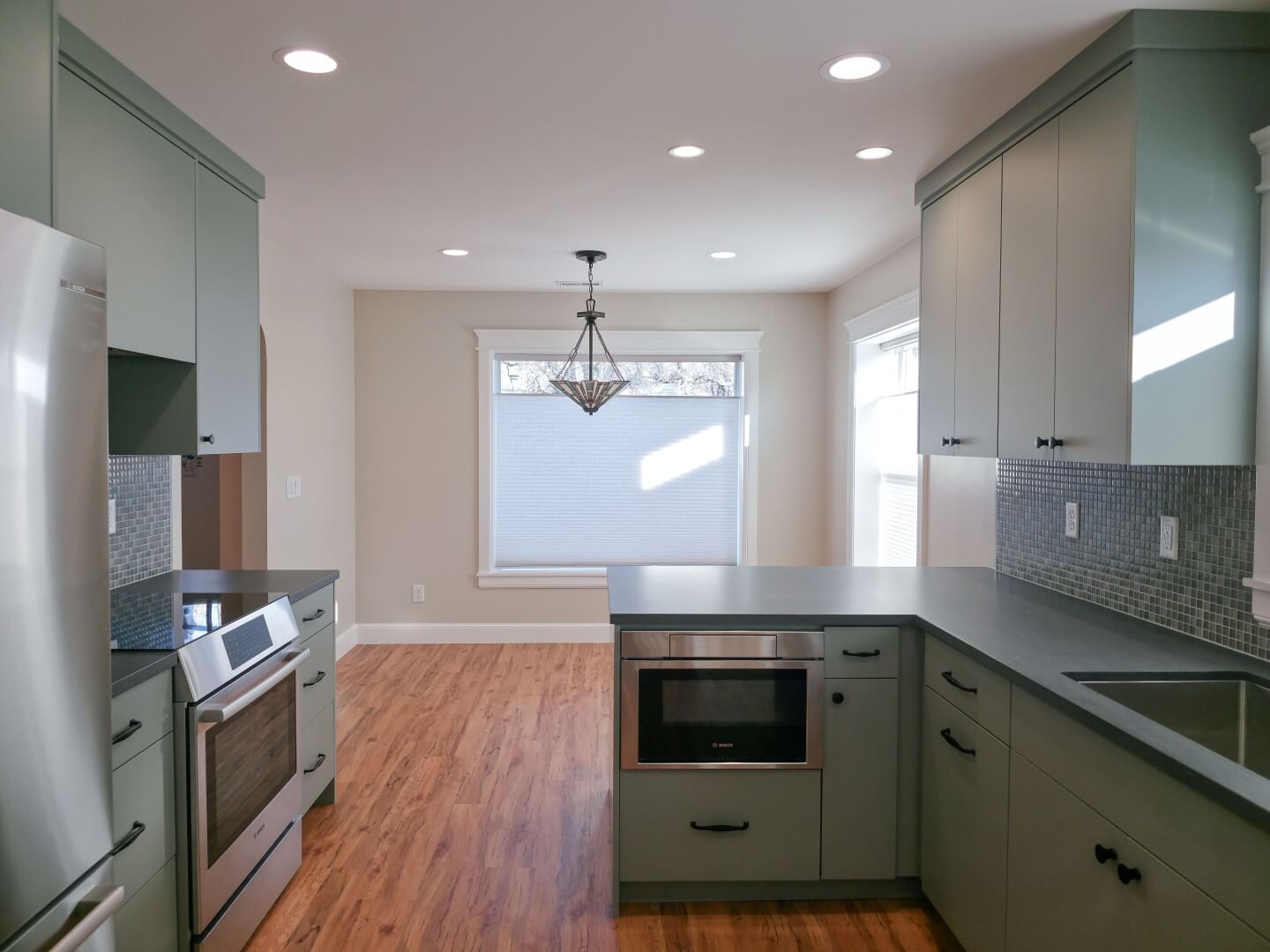 Renovated kitchen that is open to the dining room and includes a peninsula, updated appliances, and wood flooring.