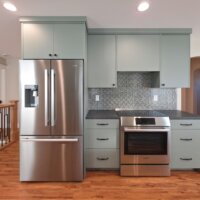 Thumbnail of http://The%20fridge,%20cabinetry,%20and%20the%20stove%20and%20oven%20along%20an%20interior%20wall.%20On%20the%20left%20is%20an%20opening%20with%20the%20staircase,%20and%20on%20the%20right%20is%20the%20dining%20room%20with%20an%20archway%20leading%20to%20the%20living%20room.