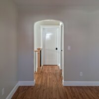 Thumbnail of http://Archway%20looking%20from%20the%20living%20room%20to%20the%20hallway.%20The%20hallway%20includes%20the%20staircase%20railing%20and%20closed%20doors%20leading%20to%20the%20primary%20suite%20and%20powder%20bathroom.