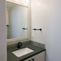 Thumbnail of http://Vanity%20in%20the%20powder%20bathroom.%20The%20vanity%20includes%20storage,%20a%20small%20counter%20area%20around%20the%20sink,%20a%20mirror,%20and%20lighting.