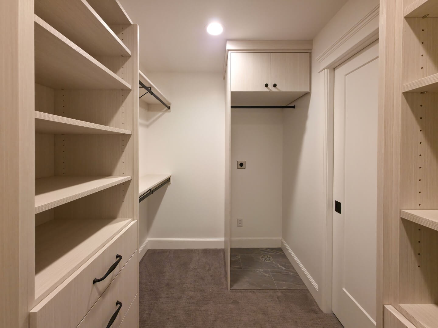 Large walk-in closet with lots of shelving and a place for a stackable washer and dryer. On the right the pocket door with access to the bedroom is closed.